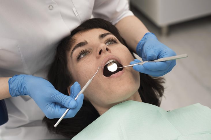 A dentist performing a teeth cleaning procedure on a woman